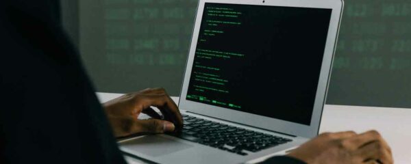 Développeur codant sur un ordinateur portable avec un écran de code en langage informatique.