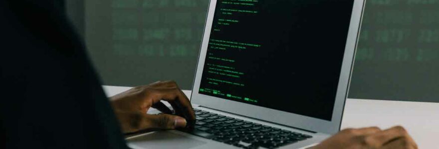 Développeur codant sur un ordinateur portable avec un écran de code en langage informatique.