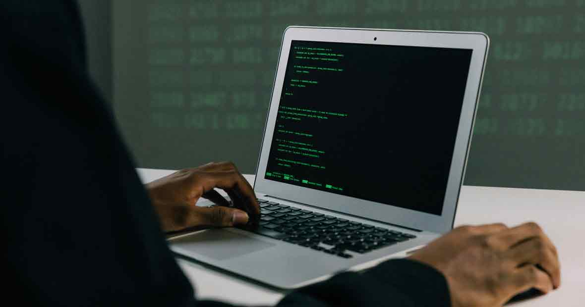 Développeur codant sur un ordinateur portable avec un écran de code en langage informatique.