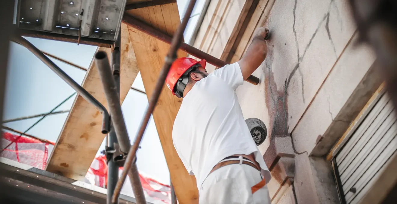 Ouvrier en équipement de sécurité travaillant sur la finition extérieure d'un immeuble résidentiel neuf en construction